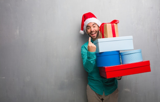 Hombre joven que llevaba un sombrero de santa con regalos invitando a venir