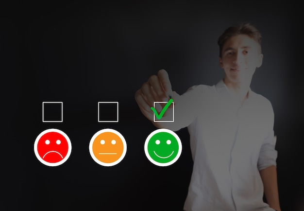 Foto hombre joven que marca el estado de ánimo feliz en el formulario de encuesta de satisfacción del cliente