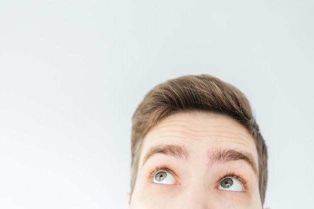 Hombre joven que mira para arriba en fondo gris claro. La cabeza del hombre