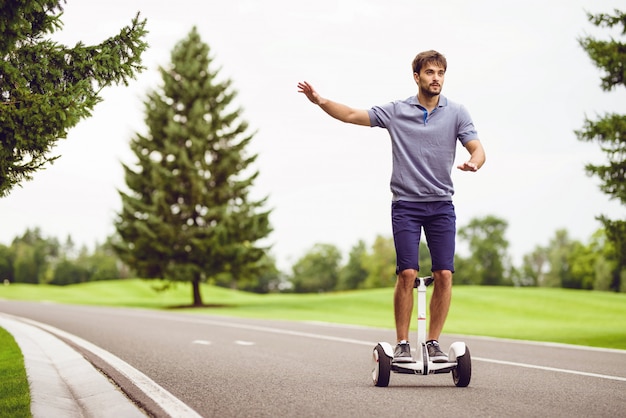 Foto hombre joven que monta un gyroboard en el camino.