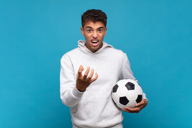Hombre joven que parece enojado, molesto y frustrado gritando, concepto de fútbol