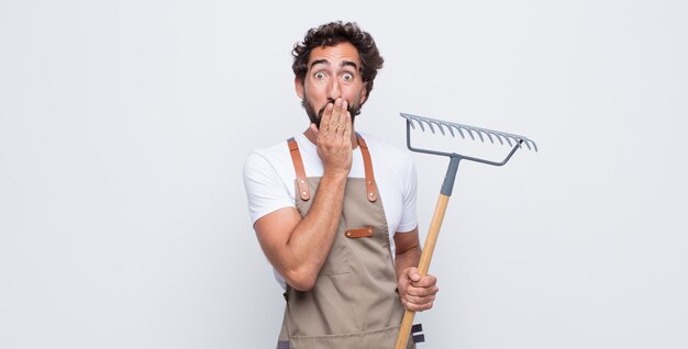 Hombre joven que parece feliz, alegre, afortunado y sorprendido cubriendo la boca con ambas manos