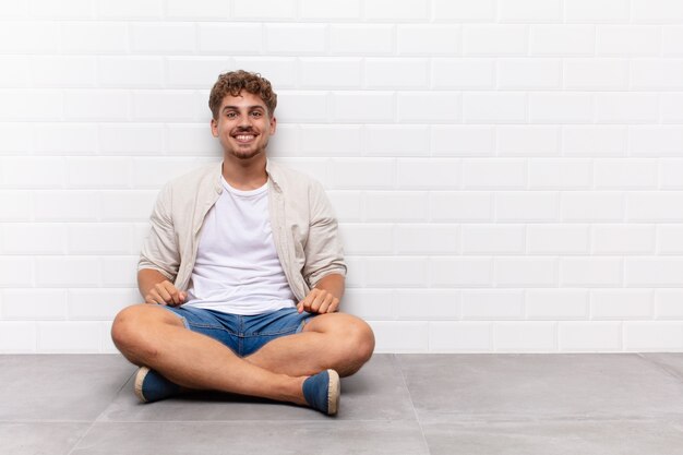 Hombre joven que parece feliz y tonto con una sonrisa amplia, divertida y chiflada y los ojos bien abiertos