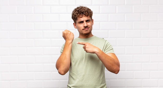 Hombre joven que parece impaciente y enojado, señalando el reloj, pidiendo puntualidad, quiere llegar a tiempo