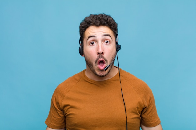 Hombre joven que parece muy conmocionado o sorprendido, mirando con la boca abierta diciendo wow