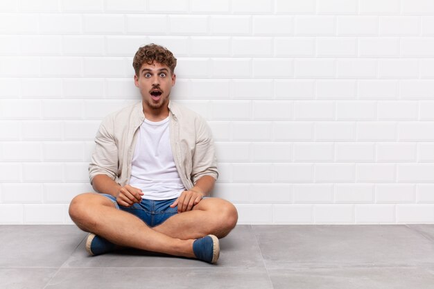 Hombre joven que parece muy conmocionado o sorprendido, mirando con la boca abierta diciendo wow