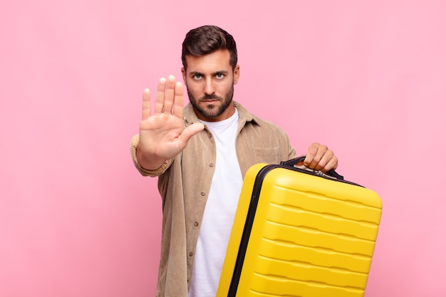 Hombre joven que parece serio, severo, disgustado y enojado mostrando la palma abierta haciendo gesto de parada. concepto de vacaciones