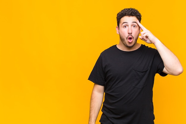 Foto hombre joven que parece sorprendido, con la boca abierta, conmocionado, dándose cuenta de un nuevo pensamiento, idea o concepto