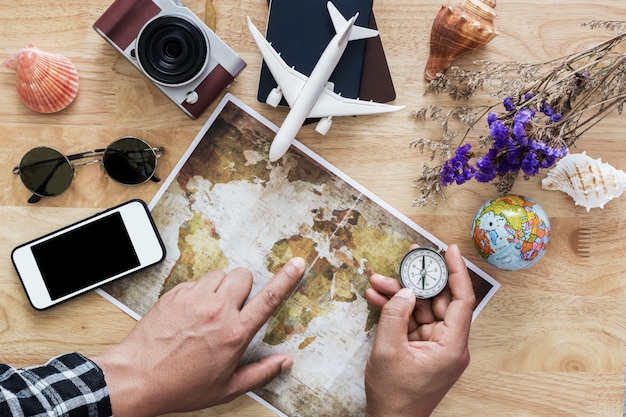 Hombre joven que planea viajar en viaje de vacaciones con el mapa. Vista superior.