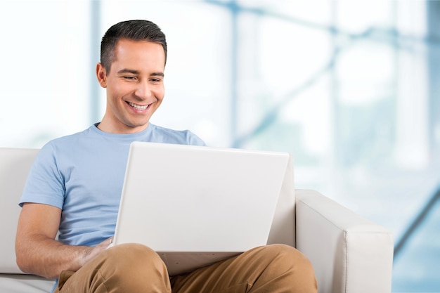 Hombre joven que se relaja en el sofá con una computadora portátil