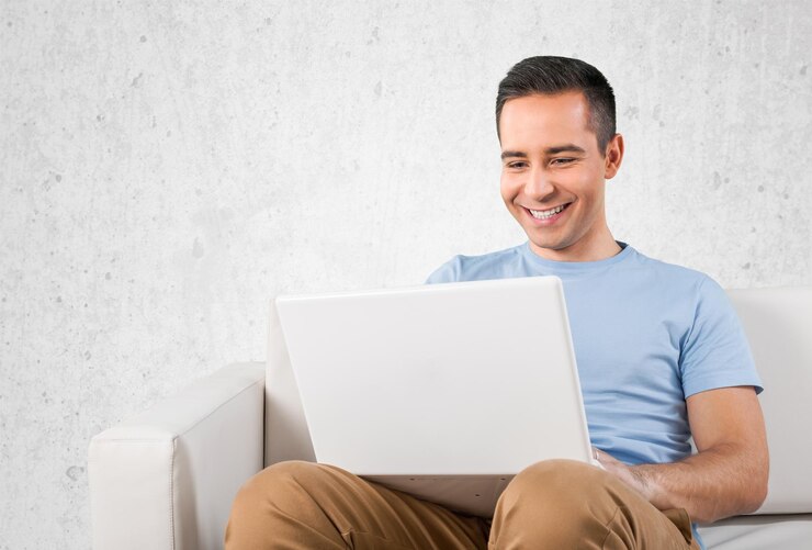 Foto hombre joven que se relaja en el sofá con una computadora portátil