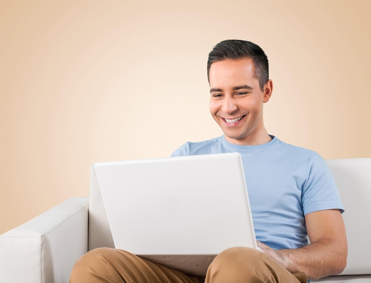 Foto hombre joven que se relaja en el sofá con una computadora portátil