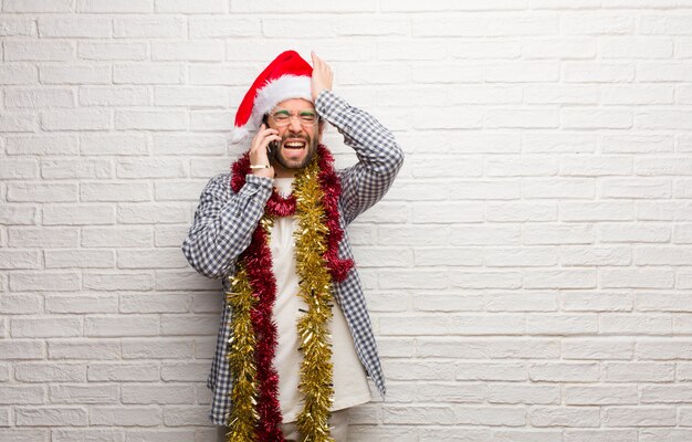 El hombre joven que se sienta con los regalos que celebran la Navidad olvidadiza, realiza algo