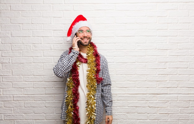 Hombre joven que se sienta con los regalos que celebran la Navidad que sueña con alcanzar metas y propósitos