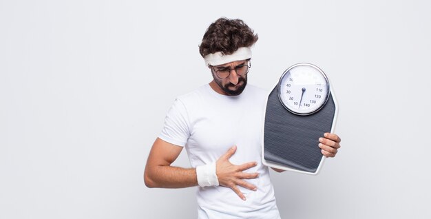 Hombre joven que se siente ansioso, enfermo, enfermo e infeliz, que sufre dolor de estómago o gripe