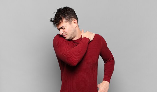 Foto hombre joven que se siente cansado, estresado, ansioso, frustrado y deprimido, que sufre de dolor de espalda o cuello