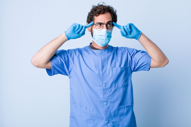 Hombre joven que se siente confundido o dudando, concentrándose en una idea, pensando mucho, buscando copiar espacio en el costado. concepto de coronavirus