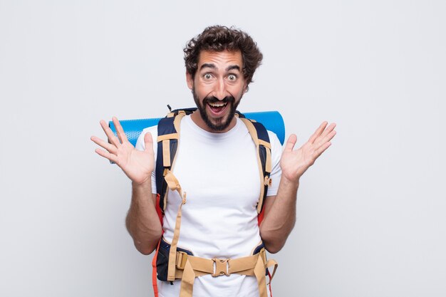 Hombre joven que se siente feliz, emocionado, sorprendido o conmocionado, sonriendo y asombrado por algo increíble