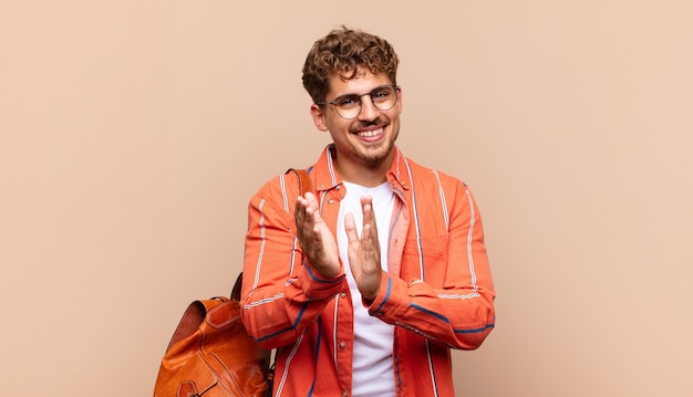 Hombre joven que se siente feliz y exitoso, sonriendo y aplaudiendo, diciendo felicitaciones con un aplauso. concepto de estudiante