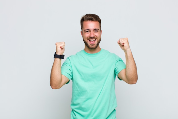 Hombre joven que se siente feliz, positivo y exitoso, celebrando la victoria, los logros o la buena suerte