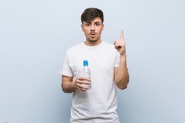 Hombre joven que sostiene una botella de agua que tiene una gran idea, concepto de creatividad.