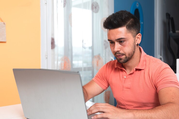 Foto hombre joven que trabaja en casa con una computadora portátil