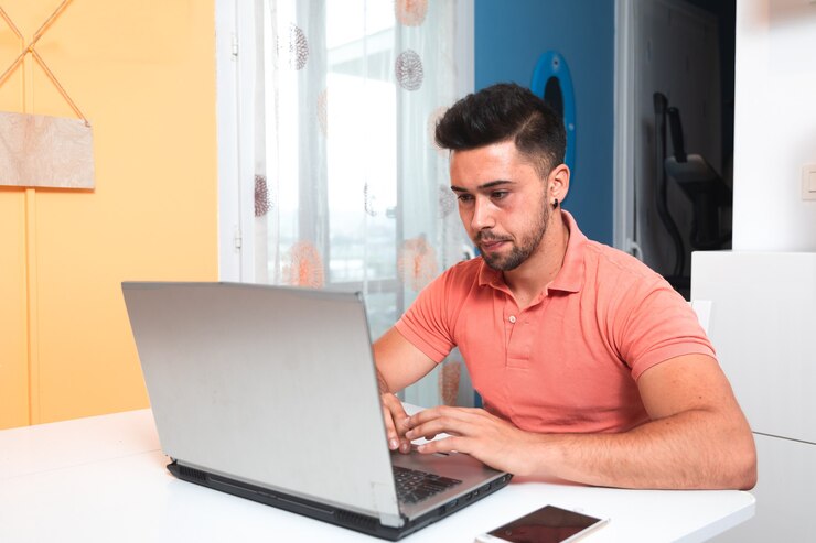 Foto hombre joven que trabaja en casa con una computadora portátil