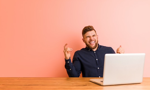 Hombre joven que trabaja con su computadora portátil alegre riendo mucho. Concepto de felicidad