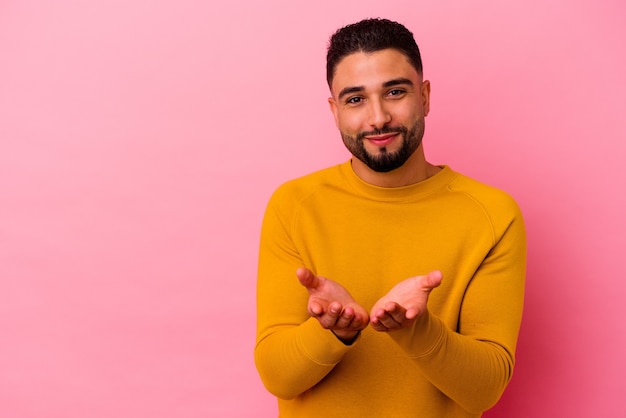 Hombre joven de raza mixta aislado en labios plegables rosados y sosteniendo las palmas para enviar beso al aire.