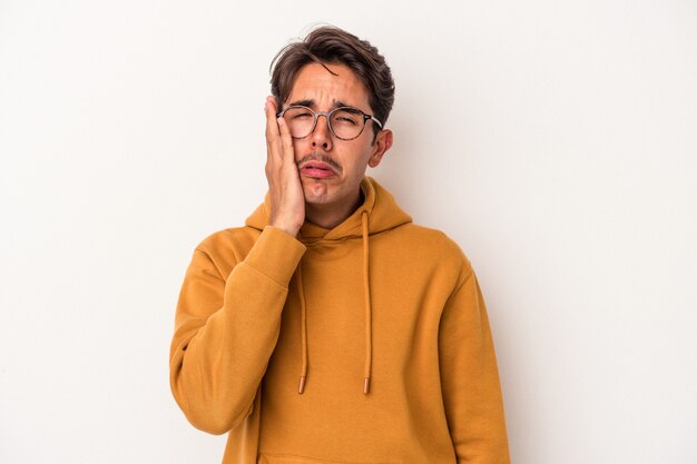 Hombre joven de raza mixta aislado sobre fondo blanco cansado y muy somnoliento manteniendo la mano en la cabeza.