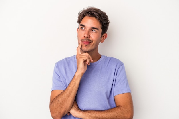 Hombre joven de raza mixta aislado sobre fondo blanco contemplando, planificando una estrategia, pensando en la forma de un negocio.