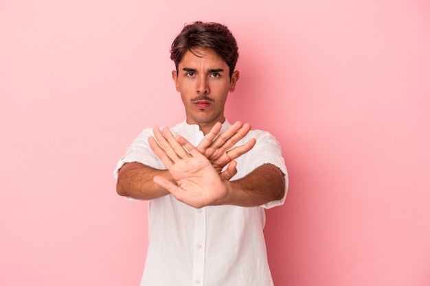 Hombre joven de raza mixta aislado sobre fondo blanco de pie con la mano extendida mostrando la señal de stop, impidiéndote.