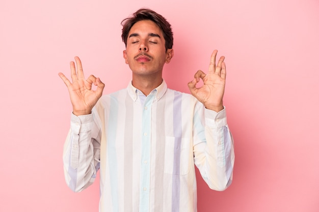 Hombre joven de raza mixta aislado sobre fondo blanco se relaja después de un duro día de trabajo, ella está realizando yoga.