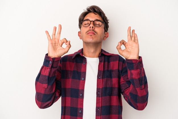 Foto hombre joven de raza mixta aislado sobre fondo blanco se relaja después de un duro día de trabajo, ella está realizando yoga.