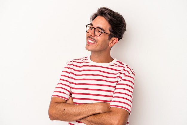 Hombre joven de raza mixta aislado sobre fondo blanco sonriendo confiado con los brazos cruzados.