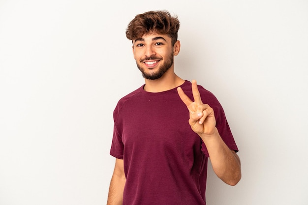 Hombre joven de raza mixta aislado sobre fondo gris que muestra el signo de la victoria y una amplia sonrisa.