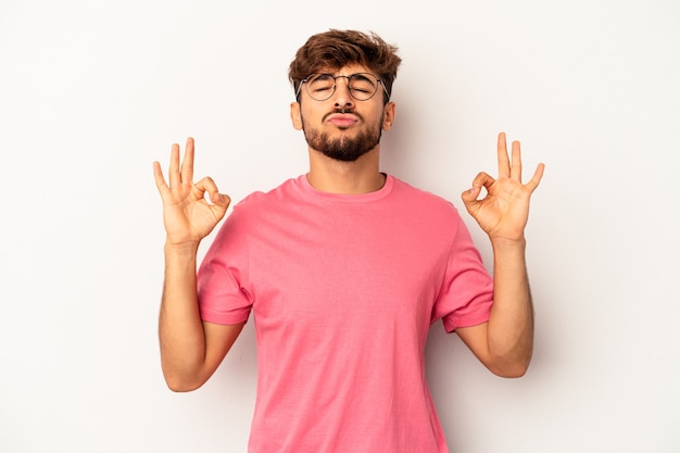 Hombre joven de raza mixta aislado sobre fondo gris se relaja después de un duro día de trabajo, ella está realizando yoga.