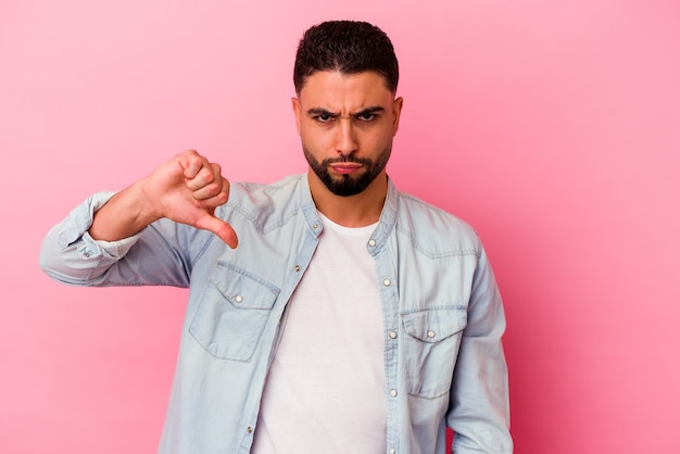 Foto hombre joven de raza mixta aislado sobre fondo rosa mostrando un gesto de aversión, pulgares hacia abajo. concepto de desacuerdo.