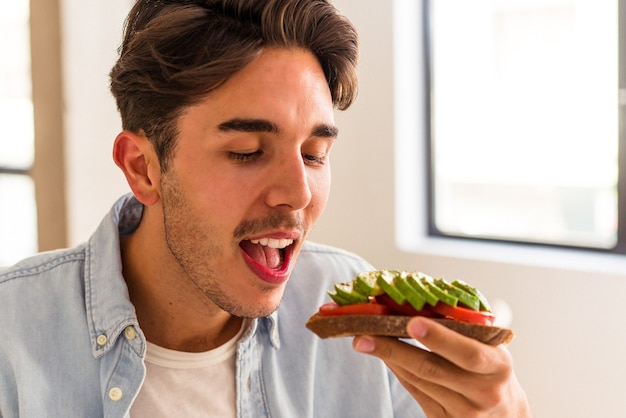 Hombre joven de raza mixta desayunando en su cocina