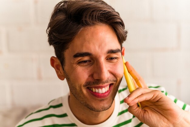 Hombre joven de raza mixta hablando por teléfono en su sofá