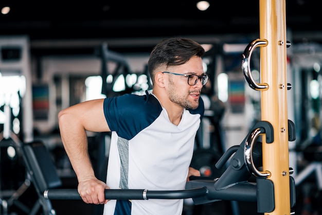 Hombre joven resuelto que ejercita en el gimnasio.