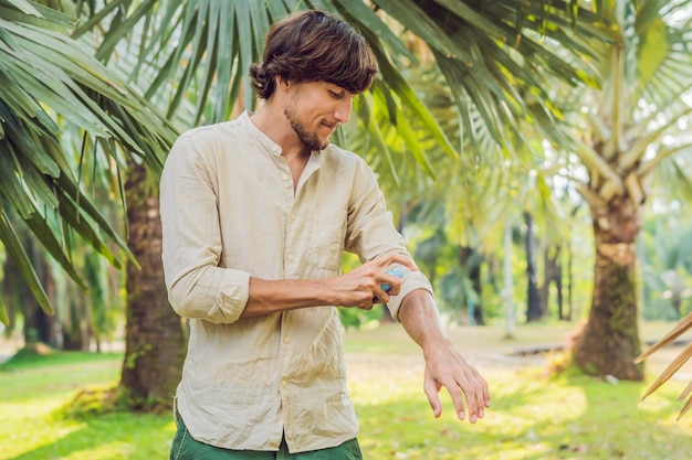 Hombre joven rociar repelente de insectos mosquitos en la protección contra insectos forrest