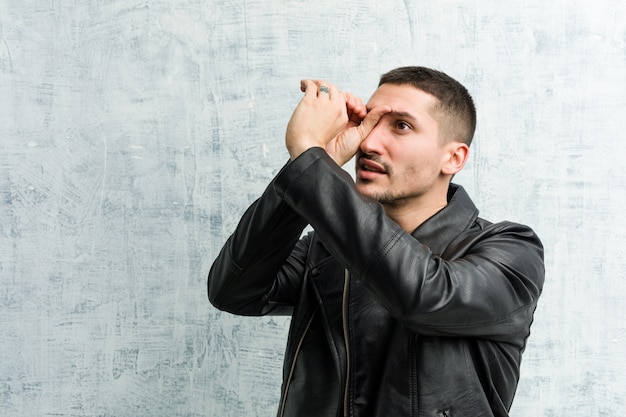 Hombre joven rockero mirando lejos manteniendo la mano en la frente.