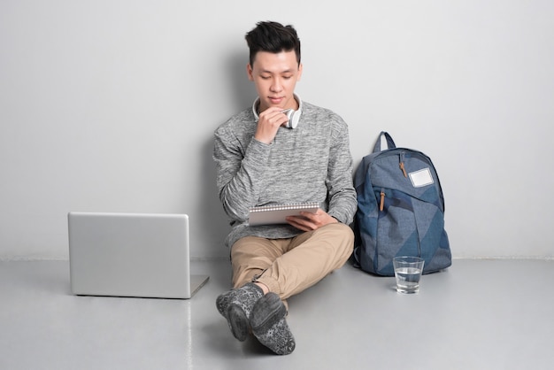 Hombre joven sentado en el suelo y usando la computadora portátil.