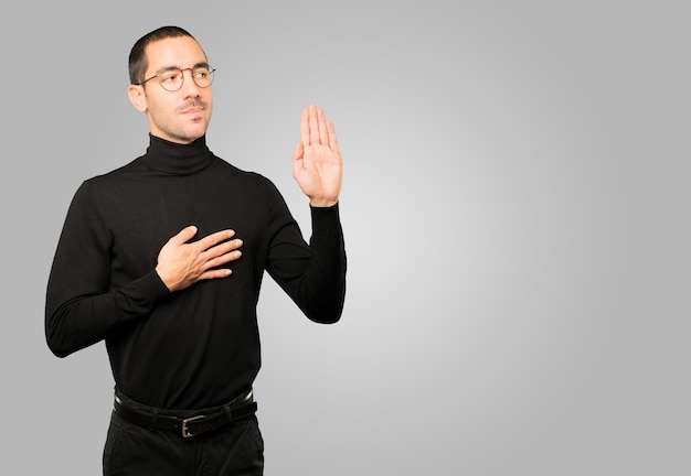 Hombre joven serio con un gesto de juramento