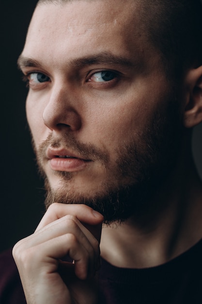 Hombre joven serio que mira en un marco en gris