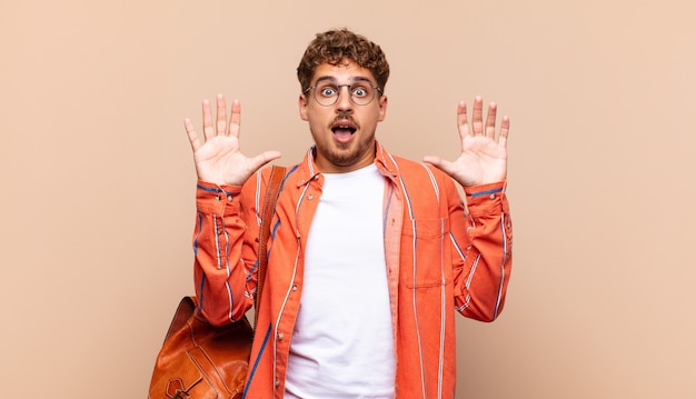 El hombre joven se siente estupefacto y asustado, temiendo algo aterrador, con las manos abiertas al frente diciendo que se mantenga alejado. concepto de estudiante