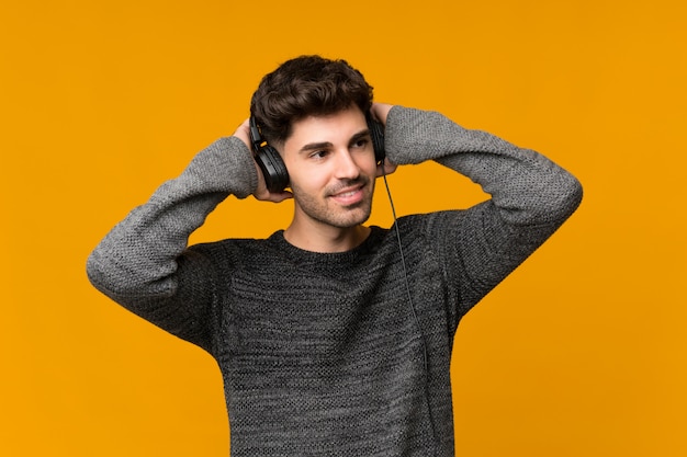 Hombre joven sobre aislado usando el móvil con auriculares