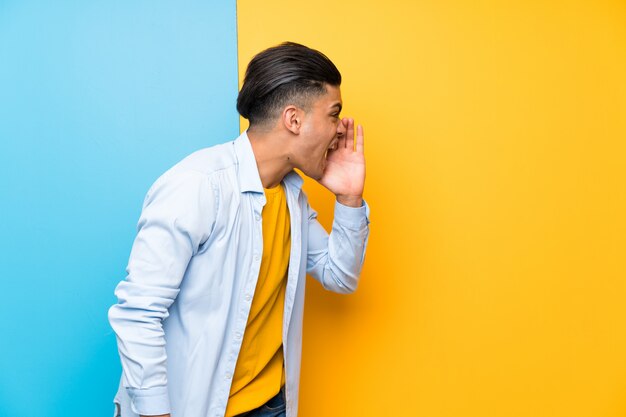 Hombre joven sobre gritos coloridos aislados con la boca abierta