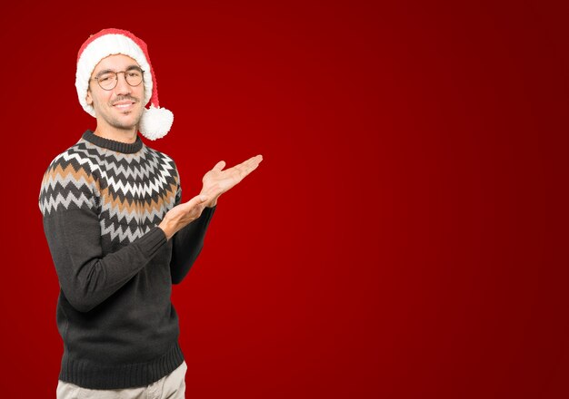 Hombre joven con sombrero de Navidad gesticulando